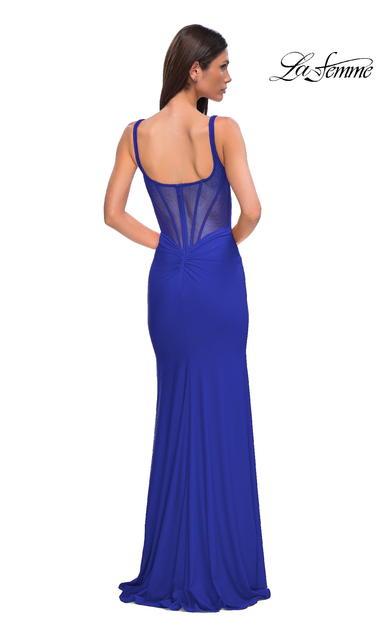A woman wears the Plunging V-Neck Long Prom Dress: La Femme 32763 in royal blue, with a sleeveless design, sheer back panel, floor-length skirt, and subtle ruching—an elegant pick for formal events.